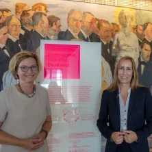 Die Landtagspräsidentin und Bettina M. Wiesmann vor dem Wandbild „Der Zug der Volksvertreter“ von Johannes Grützke in der Wandelhalle der Paulskirche